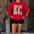 Person wearing a red sweatshirt with 'KC' design in a casual setting