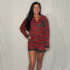 Woman wearing a red plaid shirt and black skirt lying on a white bed.