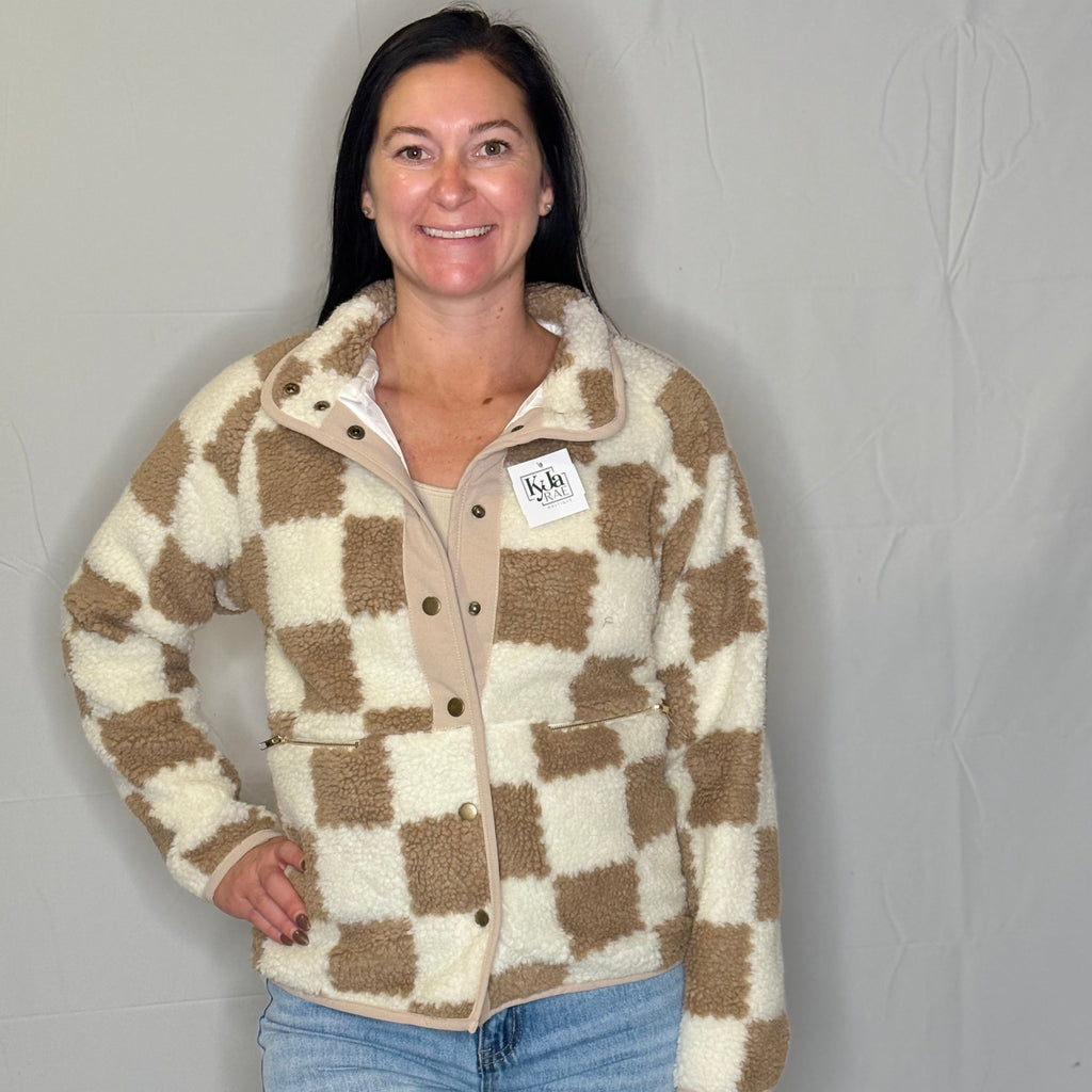 Woman wearing a checkered jacket with a visible brand tag against a plain background