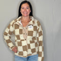 Woman wearing a checkered jacket with a visible brand tag against a plain background