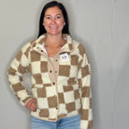 Woman wearing a checkered jacket with a visible brand tag against a plain background