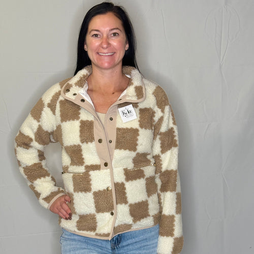 Woman wearing a checkered jacket with a visible brand tag against a plain background