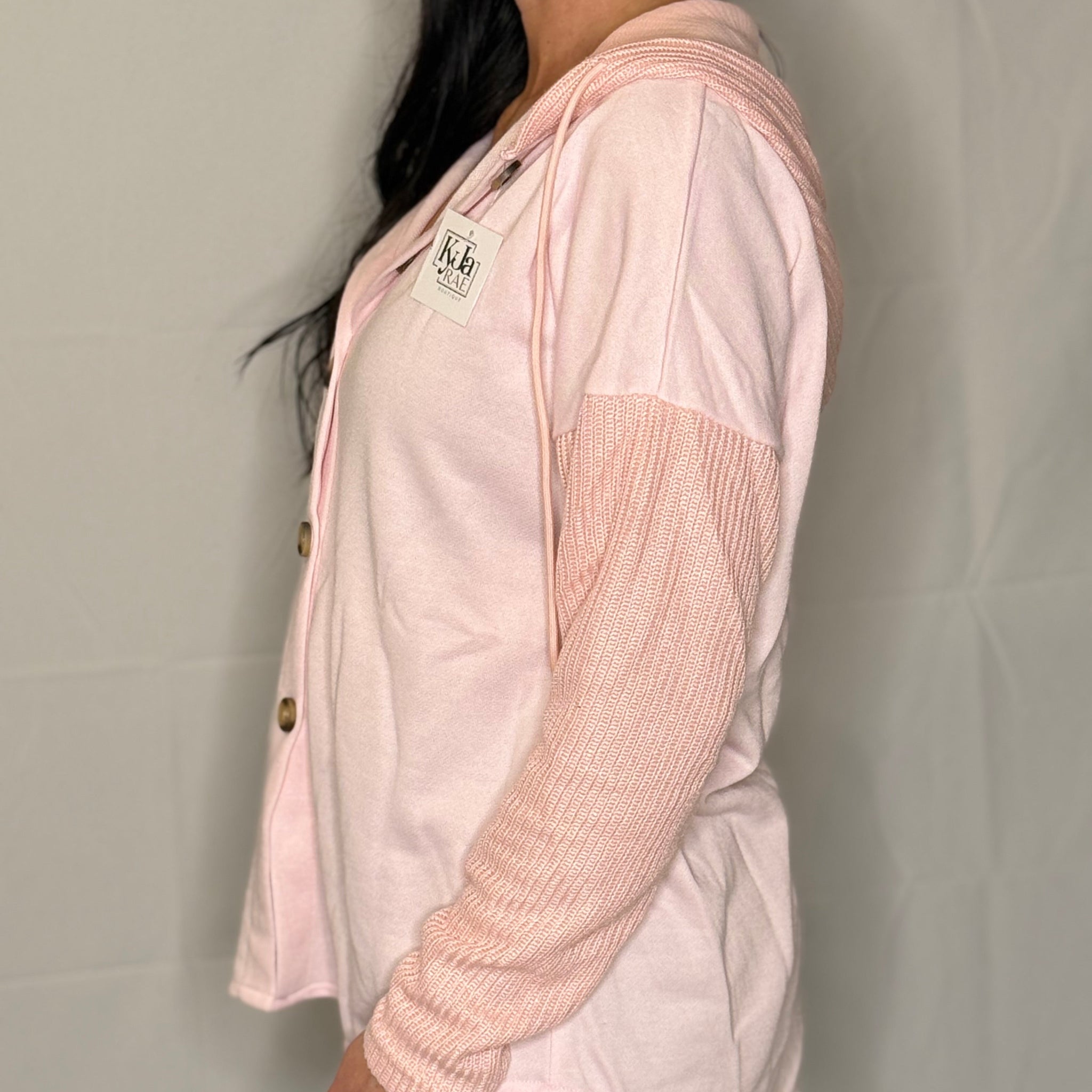 Person wearing a light pink jacket with a hood against a plain background