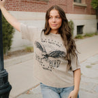 Woman wearing a graphic t-shirt with an eagle design outdoors.