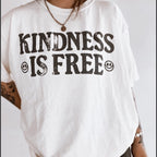 White t-shirt with 'Kindness is Free' text and smiley faces on a plain background