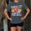Person wearing a gray 'Kansas City Football' t-shirt with a helmet graphic.