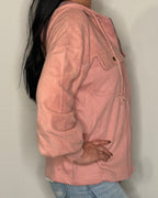 Person wearing a pink jacket against a plain background