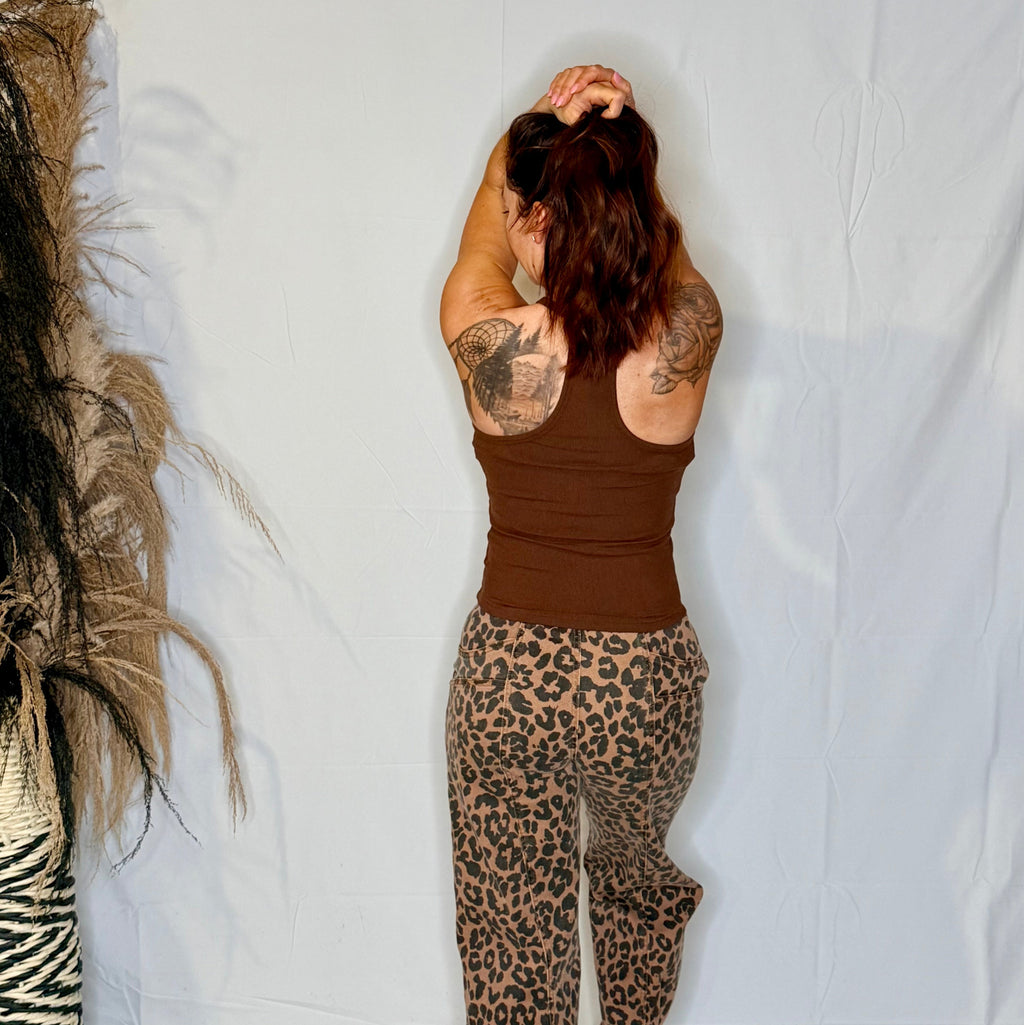 Person wearing a brown tank top and leopard print pants against a white background