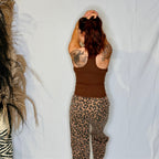 Person wearing a brown tank top and leopard print pants against a white background