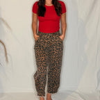 Person wearing a red top and leopard print pants against a plain background