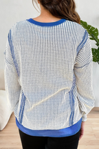 A woman viewed from the back wearing a long-sleeve knit top with a blue and white micro-check pattern and solid blue trim at the collar, cuffs, and hem.