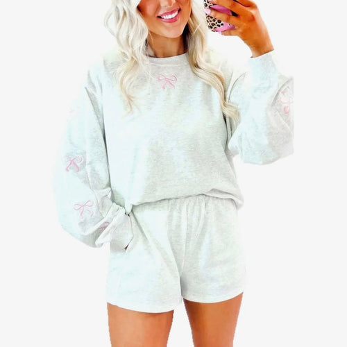 Woman wearing a light gray loungewear set with pink text on a white background