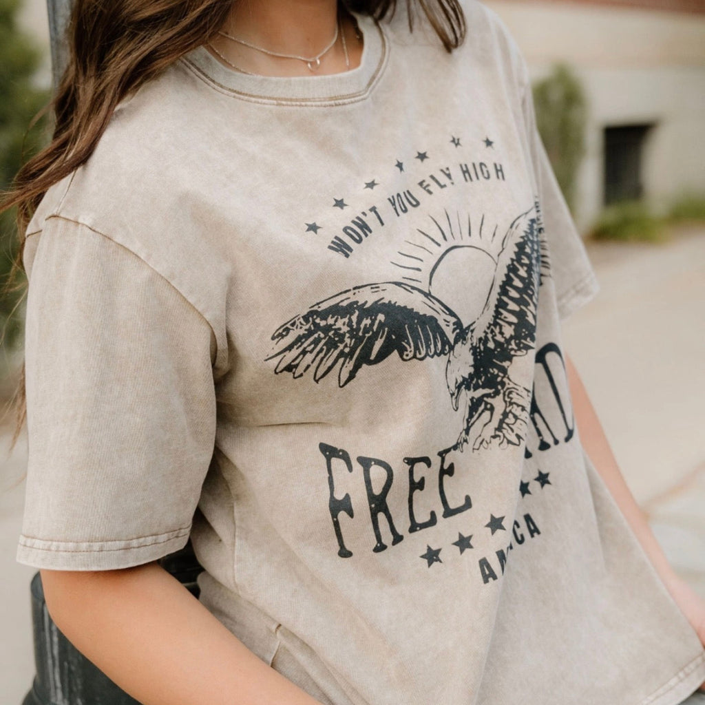 Person wearing a beige t-shirt with an eagle graphic and 'Free' text.
