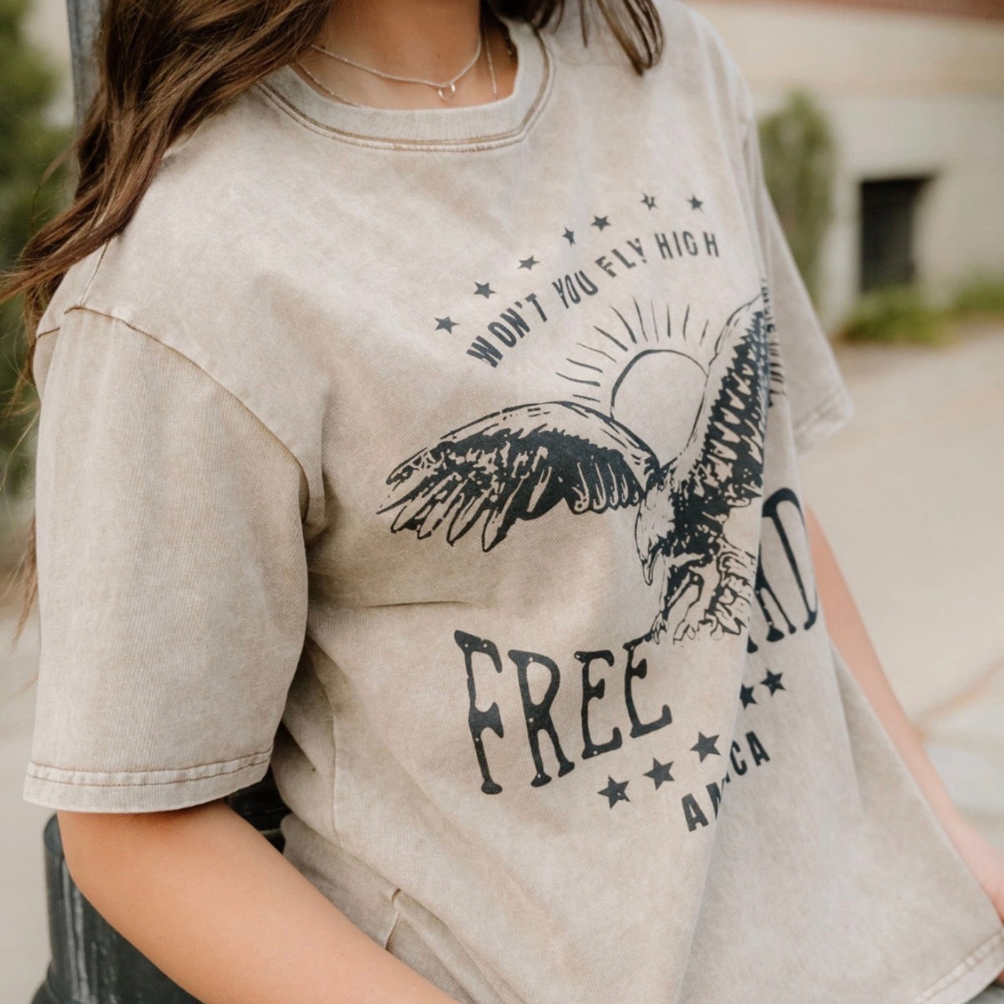 Person wearing a beige t-shirt with an eagle graphic and 'Free' text.