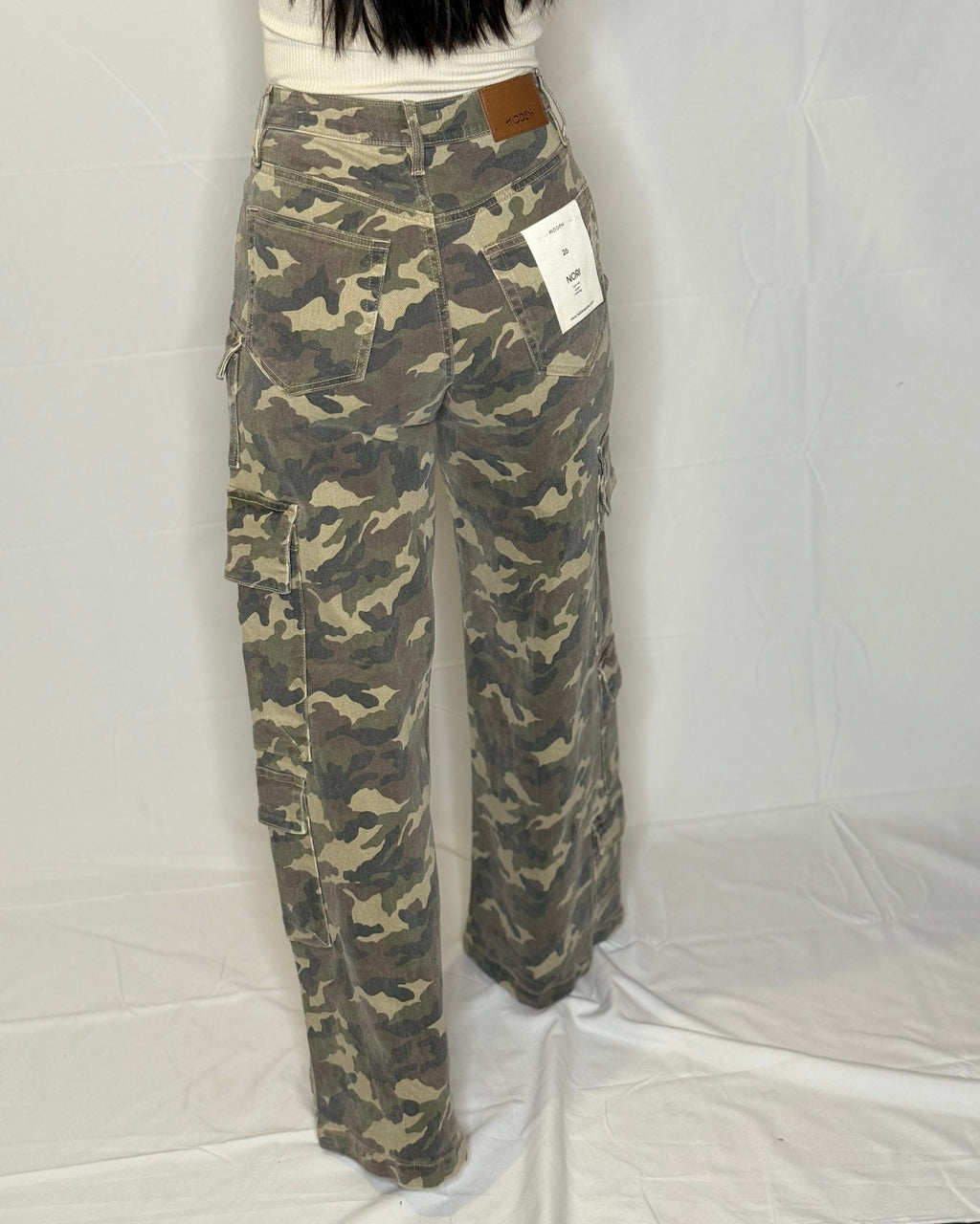 Camouflage pants with a visible brand tag on a white background