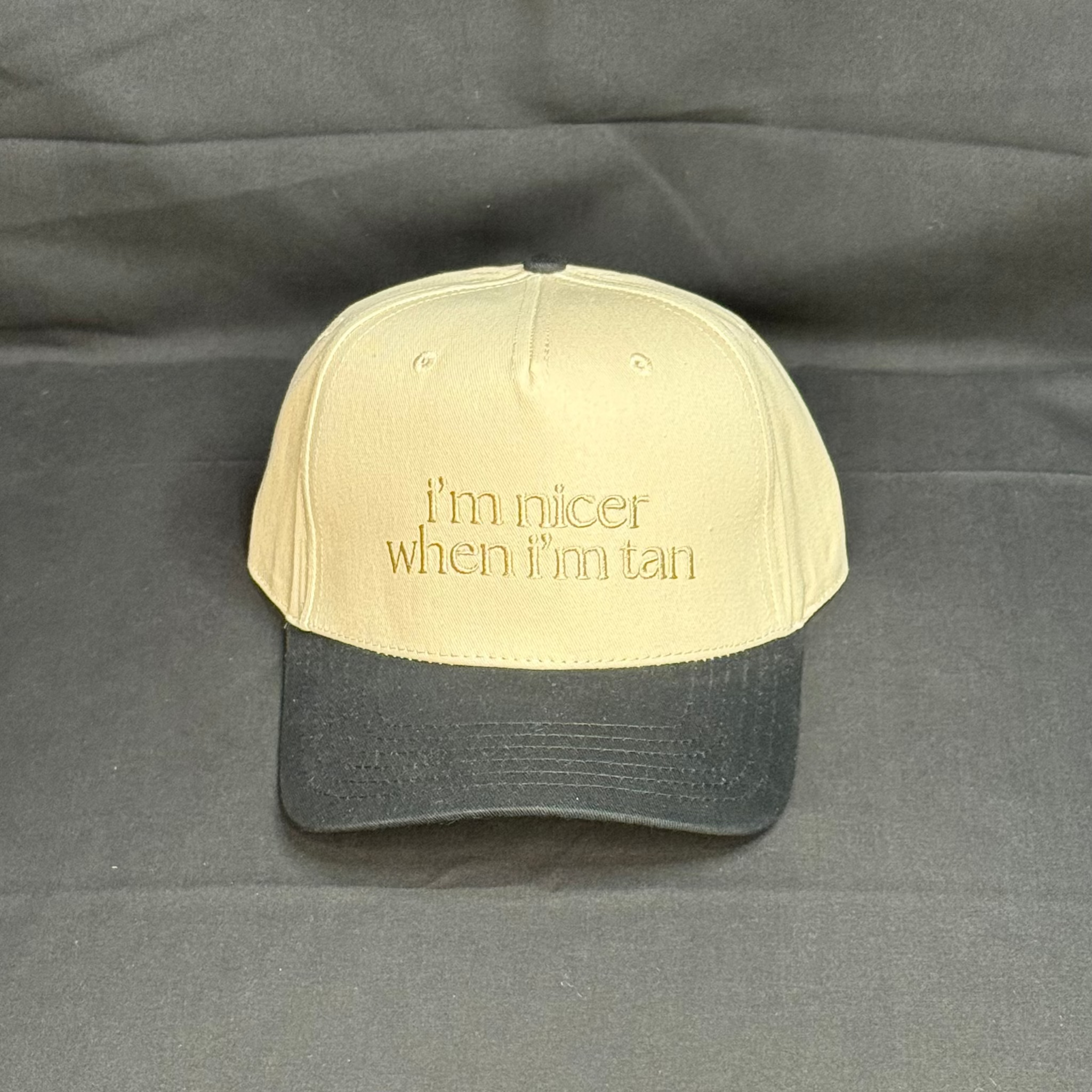 Beige and black cap with text on a gray background