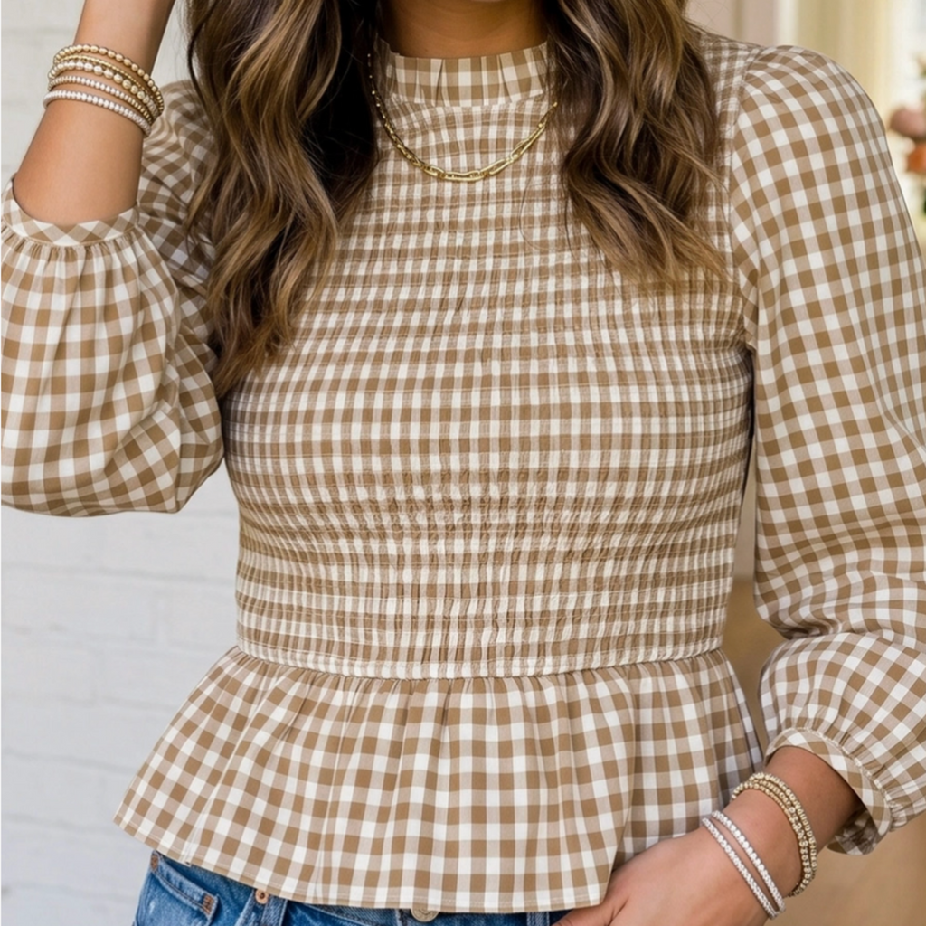 A woman wearing a beige and brown gingham long-sleeve top with a smocked waist and peplum hem, paired with blue jeans.