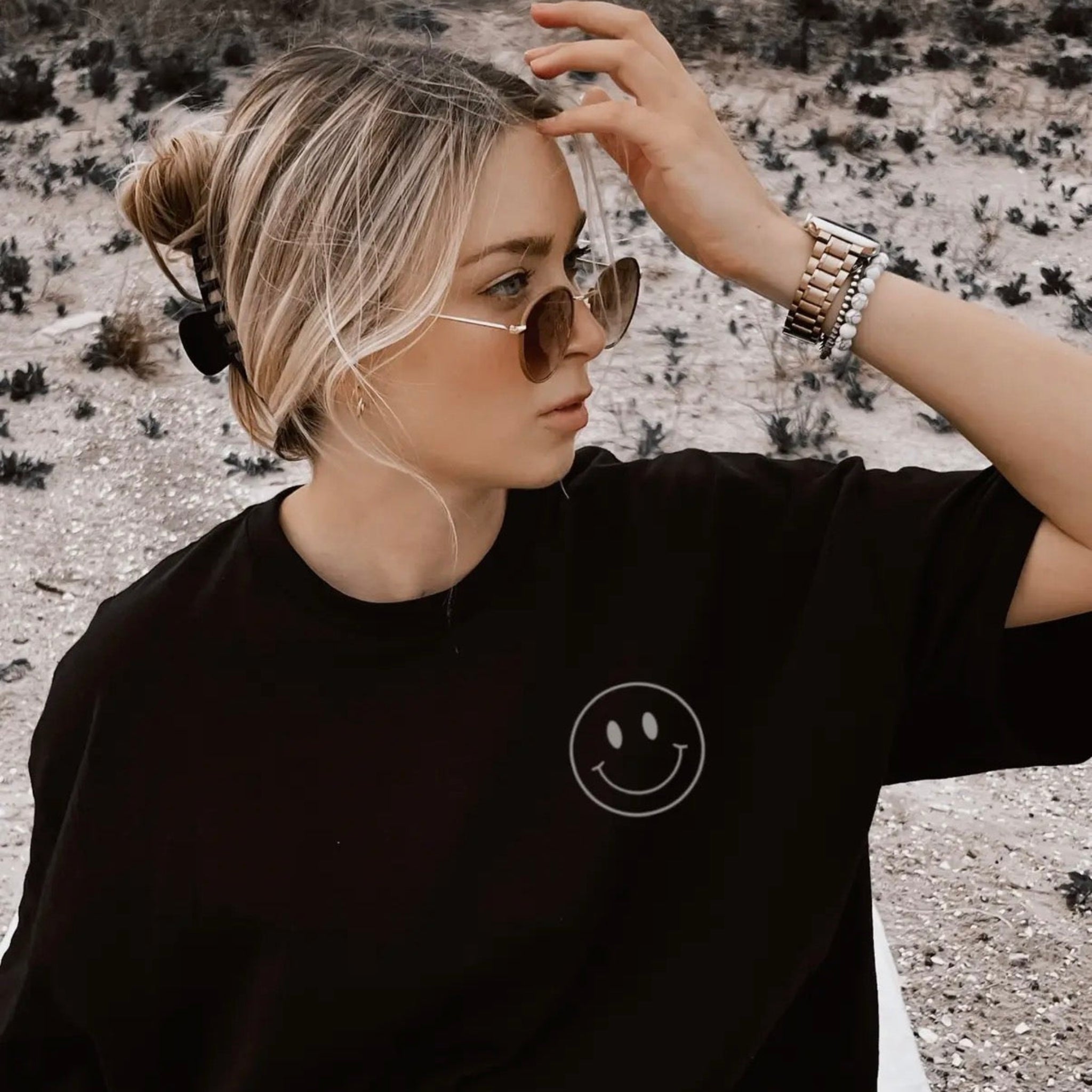 Person wearing a black t-shirt with a smiley face design outdoors.