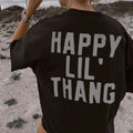 Person wearing a black t-shirt with 'HAPPY LIL THANG' text in a desert setting