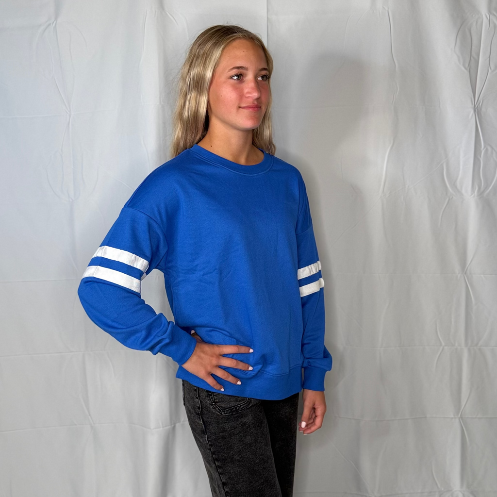 Person wearing a blue long-sleeve shirt with white stripes against a plain background