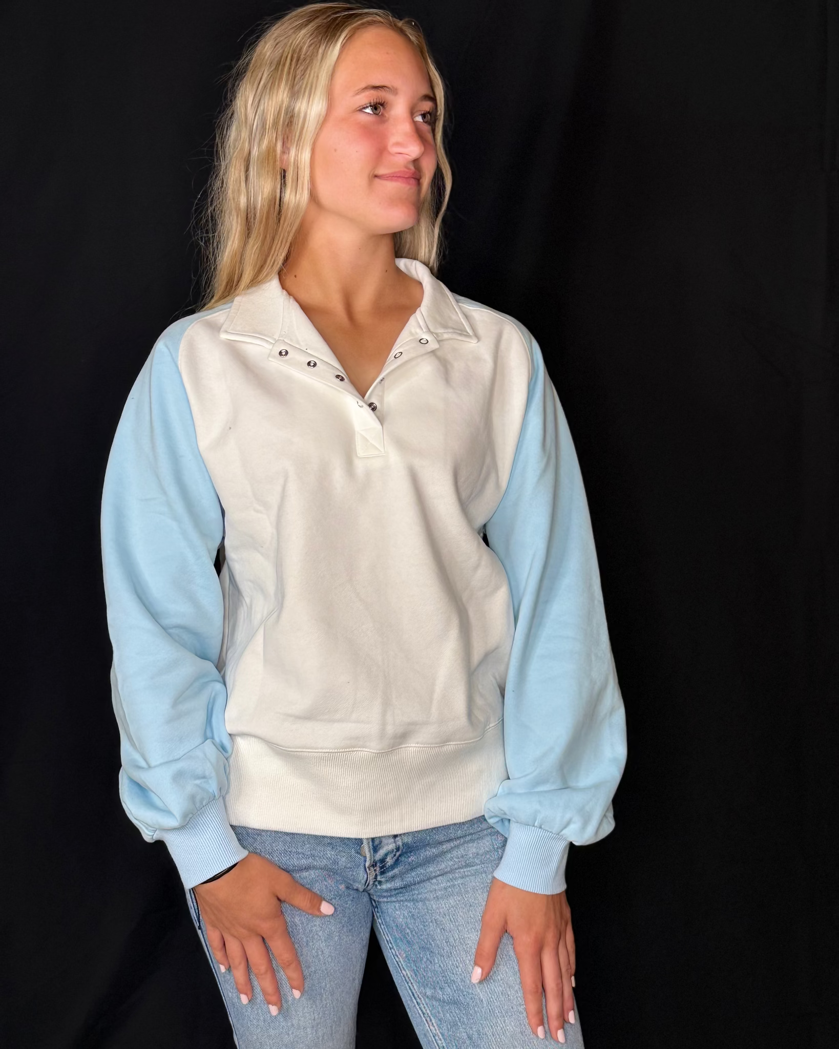 Woman wearing a light blue and white long-sleeve shirt against a black background