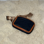 Black pouch with brown strap on a textured surface