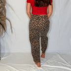 Person wearing red top and leopard print pants on a white background