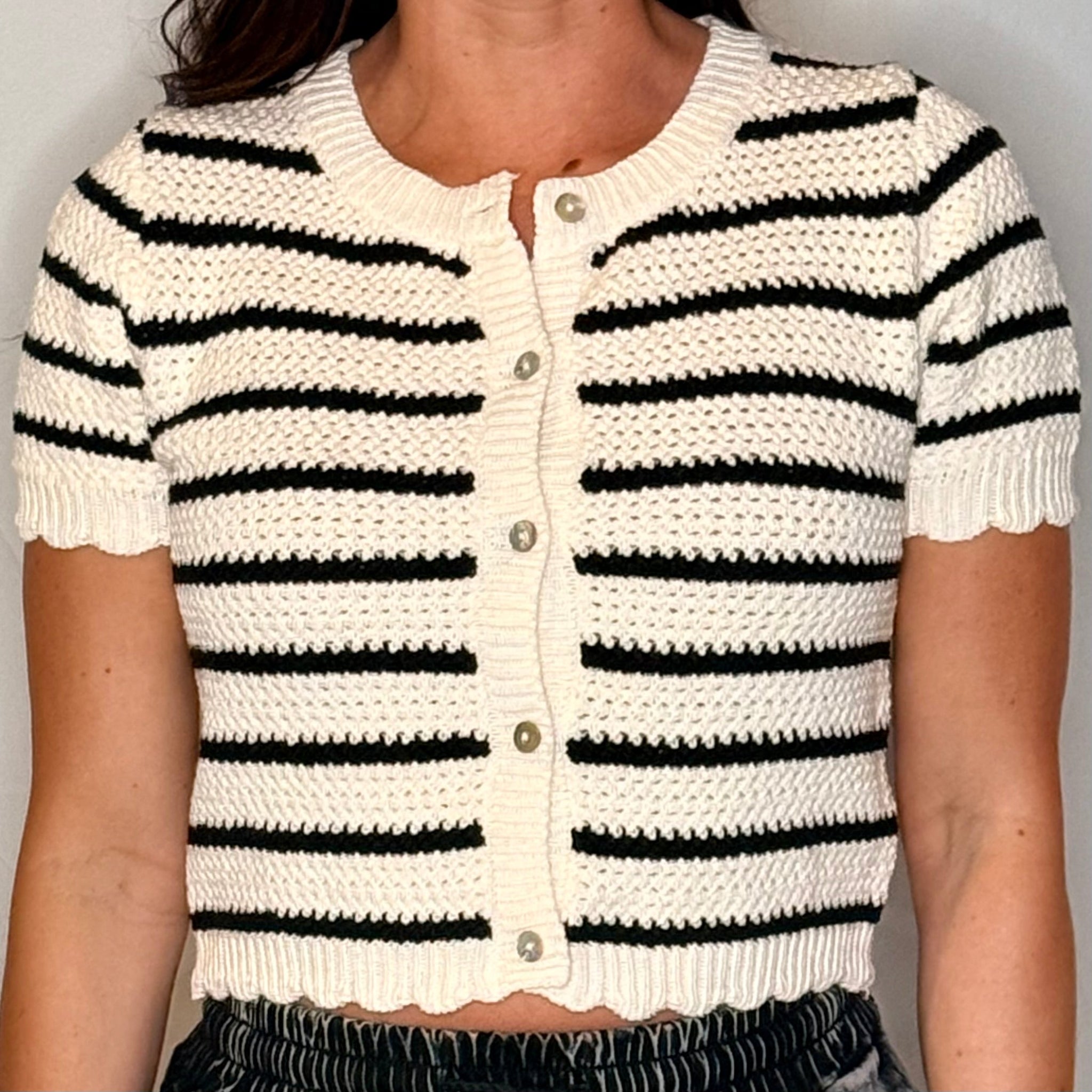 White and black striped short-sleeve cardigan on a plain background