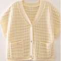 A cream-colored waffle-knit cardigan sweater with short sleeves, a V-neck, and two front patch pockets, hanging on a wooden hanger against a light background.