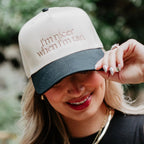Woman wearing a cap with text, smiling outdoors